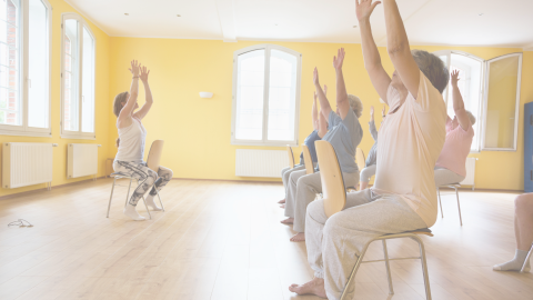 photo of people seated in chairs with arms raised in yellow room