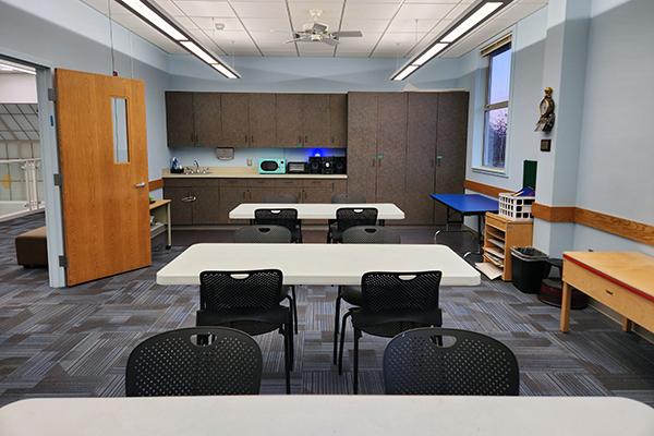 photo of medium-sized room with blue walls and carpet, white tables, sink and grey cabinets